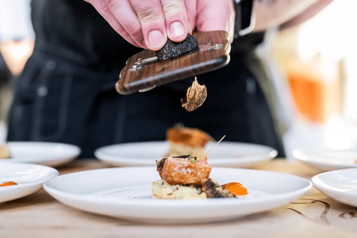 chef grating truffle over pork dish